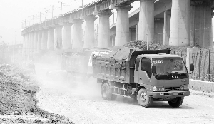 双麒路上,倾倒垃圾的车辆驶过,扬尘弥漫